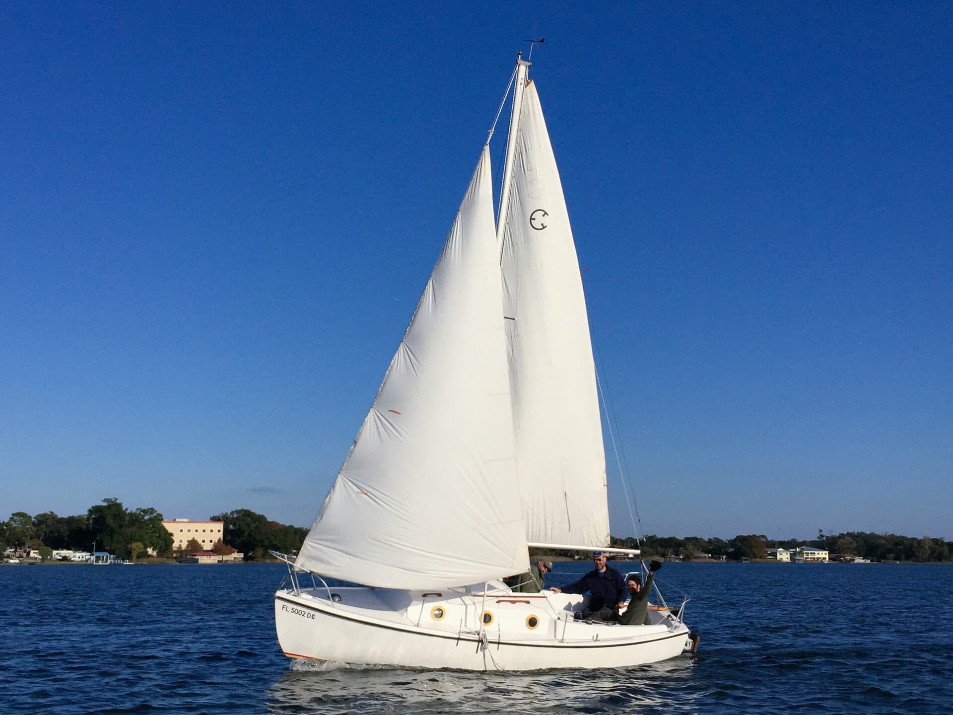 Sailor at the helm of a Com-Pac sailboat on Lake Fairview
